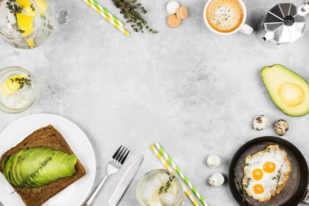 Desayuno tradicional: tostadas de pan de centeno con aguacate, huevos fritos de huevos de codorniz, café, limonada sobre un fondo claro. Vista superior, copia espacio. Fondo de alimentos