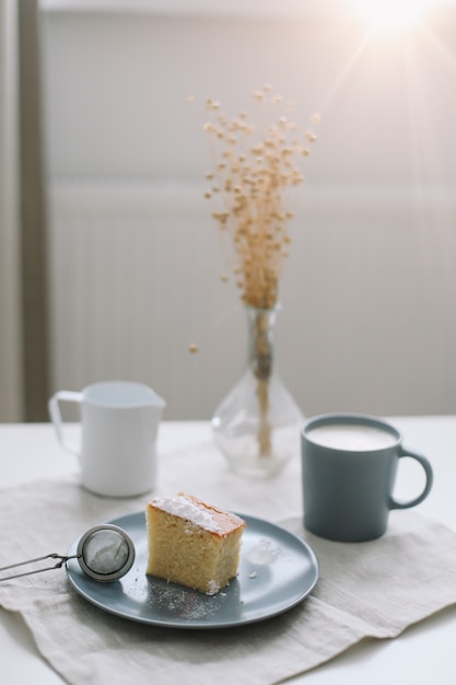 Desayuno con un trozo de tarta casera en un plato y una taza de café