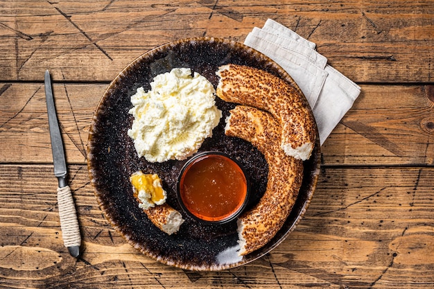 Desayuno turco tradicional: crema coagulada kaymak, bagel simit y miel. Fondo de madera. Vista superior.