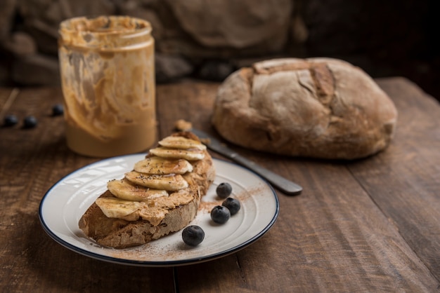 Foto desayuno vegano con pan rústico, mantequilla de maní, plátano, arándanos