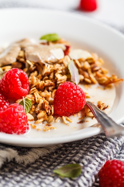 Desayuno vegano saludable - crumble de avena al horno con bayas y mantequilla de nuez en un plato blanco.