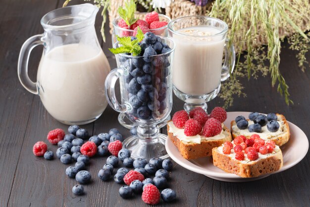 Desayuno vegano saludable. Granola de avena con leche de avena y bayas sobre mesa de madera.