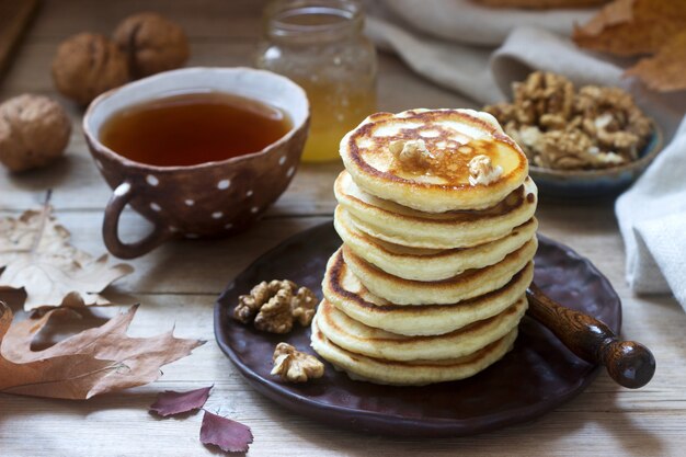 Desayuno vegetariano de buñuelos con miel, nueces y té. Bodegón otoñal.