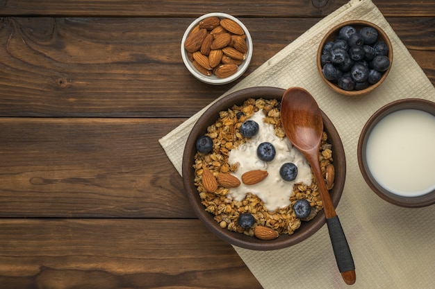 Desayuno vegetariano de muesli, nueces, bayas y leche sobre una mesa rústica. Endecha plana.