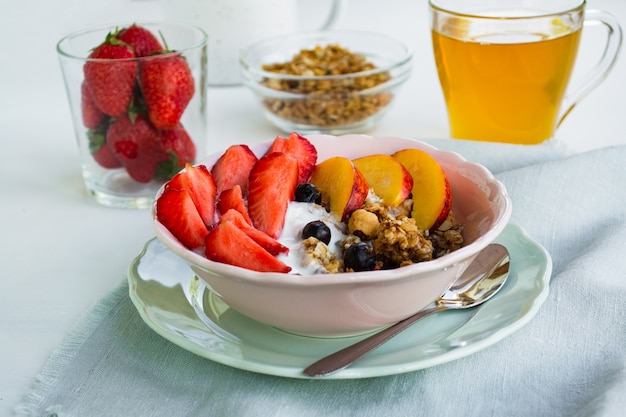 Desayuno vegetariano saludable. Un bol de granola, bayas y fruta.