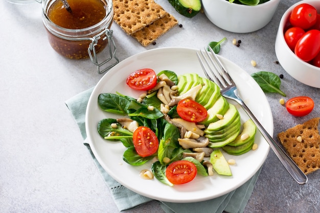 Desayuno vegetariano verde en un tazón de aguacate, champiñones, tomate cherry, piñones, espinacas y aderezo con salsa vinagreta Concepto de dieta de comida vegetariana