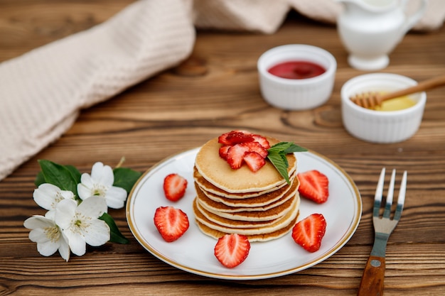 Foto desayuno de verano saludable, panqueques americanos clásicos caseros con bayas frescas y miel sobre un fondo de madera. deliciosos pasteles, postre.