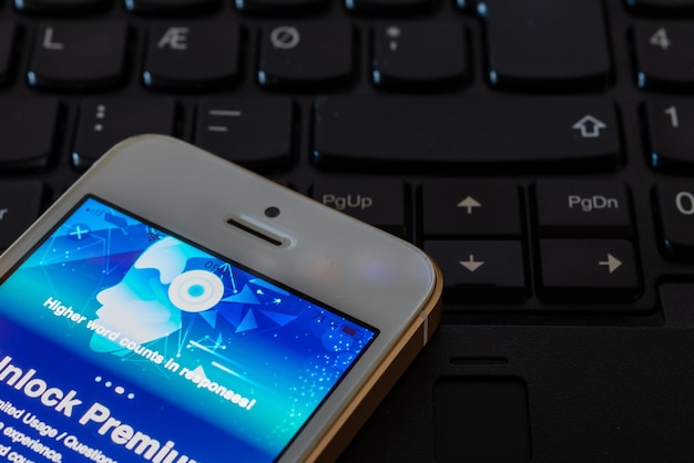 Desbloquear Premium en la aplicación AISmartphone en el teclado de la computadora portátil con el sitio web ChatGPT en la pantalla Desarrollado por OpenAITelsiaiLithuania04272023