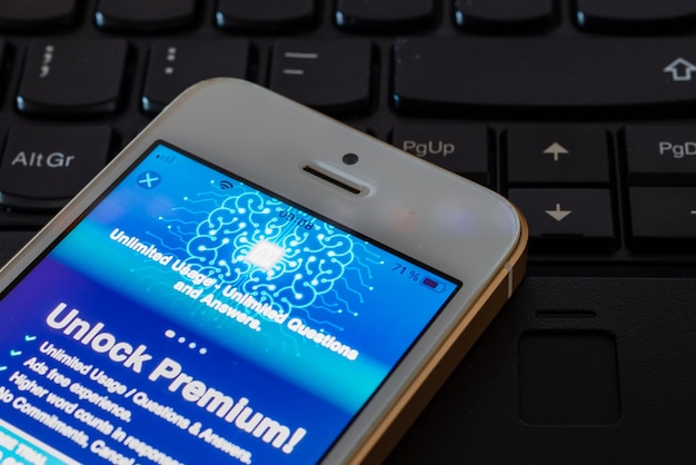 Desbloquear Premium en la aplicación AISmartphone en el teclado de la computadora portátil con el sitio web ChatGPT en la pantalla Desarrollado por OpenAITelsiaiLithuania04272023