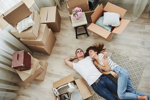 Descansando. deitada no chão. casal jovem alegre em seu novo apartamento. concepção de movimento.