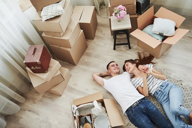 Descansando. Deitada no chão. Casal jovem alegre em seu novo apartamento. Concepção de movimento.