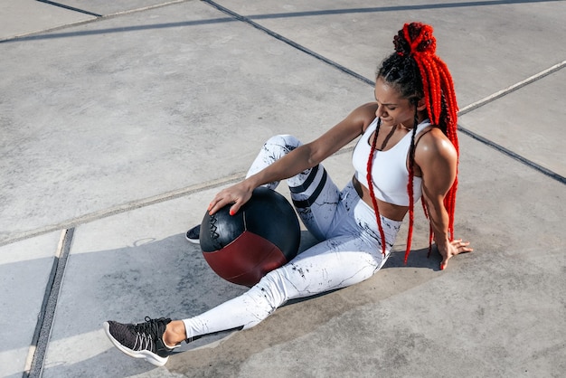 Descansando Mujer atlética haciendo ejercicio con pelota médica Fuerza y motivaciónFoto de mujer deportiva en ropa deportiva de moda