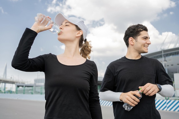 Descanse, beba água, um jovem casal faz um treino de fitness correndo juntos