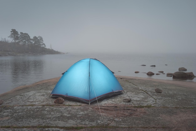 Descanse en una carpa lejos de la civilización Costa de Granito Mañana nublada Carpa turística solitaria en la costa de granito Vista atmosférica nublada