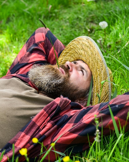 Descanso en el campo Granjero hombre barbudo descansa después del día de trabajo Granjero relajarse en la hierba verde Concepto de ecología Vacaciones de verano Entorno ecológico Descanso de verano Unidos con la patria La naturaleza es mi hogar