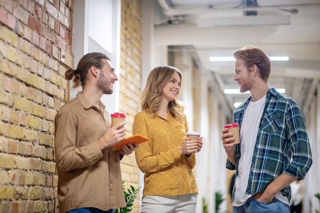 Descanso. Compañeros de trabajo jóvenes hablando y sonriendo durante la pausa para el café