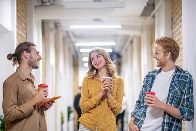 Descanso. Compañeros de trabajo jóvenes hablando y sonriendo durante la pausa para el café