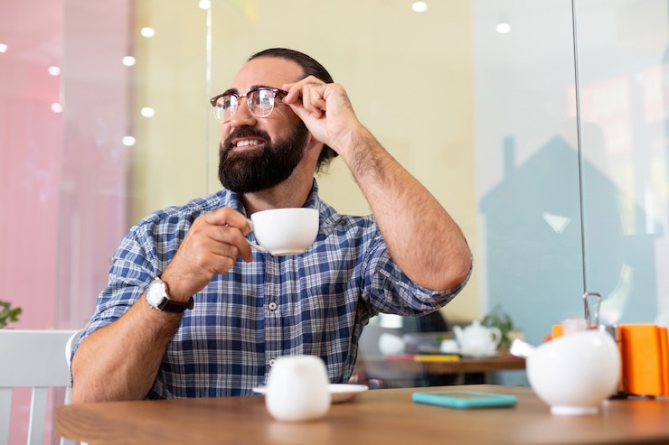 Foto descanso. exitoso empresario agradable barbudo con gafas con pausa para el café en la cafetería