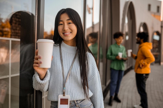 Descanso. Grupo de jóvenes parados cerca del edificio y tomando café.