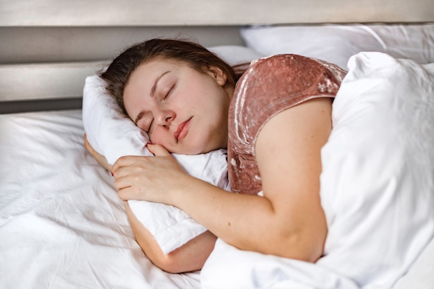 Descanso mujer ojos cerrados dormir en su cama y relajarse por la mañana.