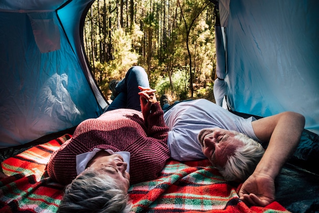 El descanso de las parejas ancianas se acuesta dentro de una carpa en un campamento libre libre en el bosque