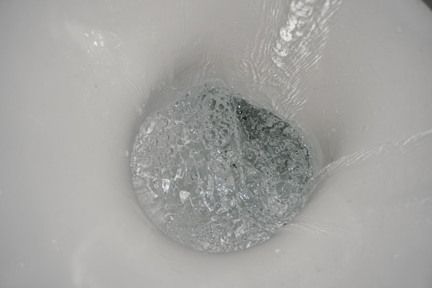 Descarga do vaso sanitário. Respingo de água. A água escorre pelo vaso sanitário. Close-up de água.