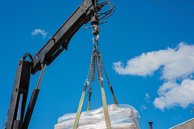 Descarga de losas de pavimento de un camión Hombres descargan losas de pavimento usando un manipulador Trabajadores descargan materiales de construcción de una máquina grande