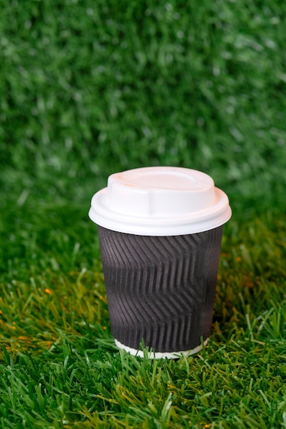 Descartável, papel, xícara de café preta com tampa branca na grama verde