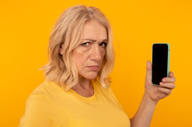 Desconfíe de la mujer enojada con el teléfono usándolo aislado en el estudio amarillo.