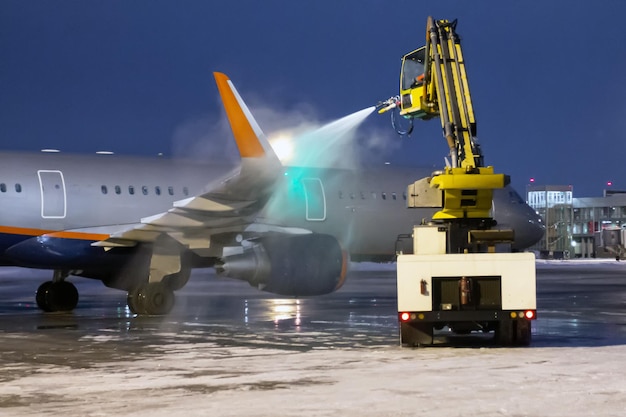 Descongelamento à terra de um avião de passageiros no avental noturno do aeroporto