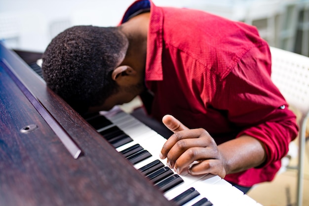 Descontente músico bonito afro-americano chateado cantando e ensinando a tocar piano