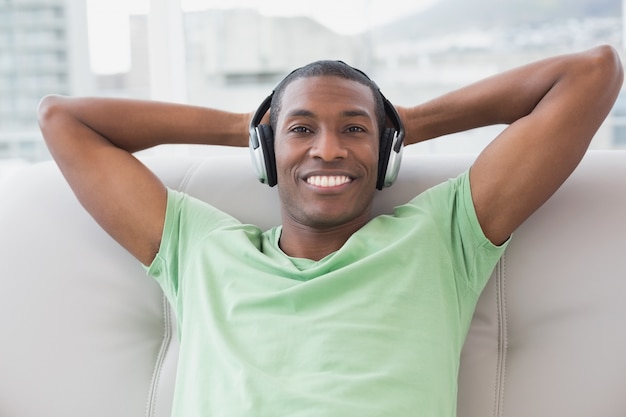 Descontraído Afro homem com fones de ouvido sentado no sofá