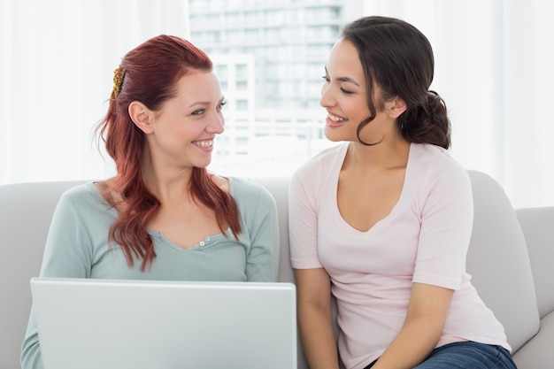 Descontraído jovens amigas usando laptop em casa