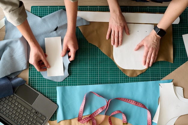 Descripción general de las manos de dos curtidoras con patrones de papel de coser