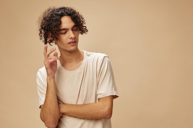 Foto desdichado descontento impresionante hombre curvilíneo bronceado en camiseta básica con asco mira a un lado posando aislado en fondo beige nueva oferta de colección de moda gente concepto de emociones lugar libre para anuncio