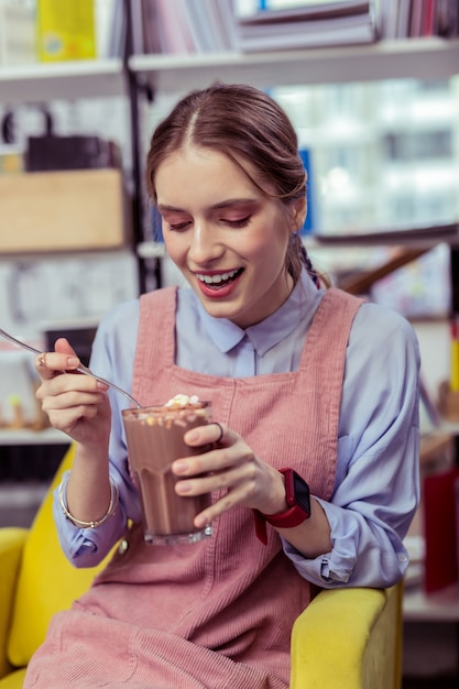 Deseando un bocado. Alegre joven cogiendo mini malvaviscos de cristal de cacao con una cuchara de metal larga