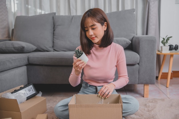 Desempaque el paquete y abra el paquete cuando compre en línea y realice una buena entrega. Estilo de vida de la mujer asiática en la sala de estar en casa. Distanciamiento social y nueva normalidad.