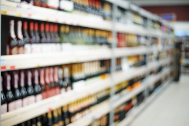Desenfoque del departamento de alcohol en un supermercado Botellas de vino y champán en los estantes Resumen fondo interior de la tienda borrosa