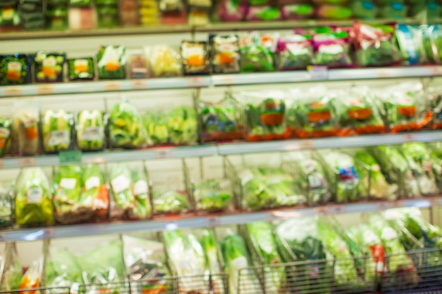 Desenfoque desenfocado de una estantería de compras de verduras y frutas puestas en ellos en el supermercado de alimentos