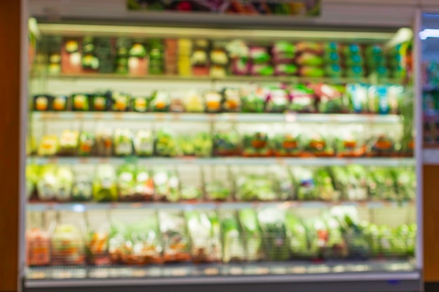 Desenfoque desenfocado de una estantería de compras de verduras y frutas puestas en ellos en el supermercado de alimentos