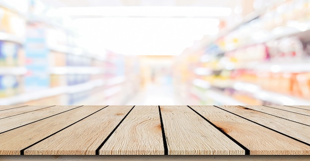 Desenfoque de fondo de tienda de conveniencia de supermercado local con mesa de madera perspectiva beige