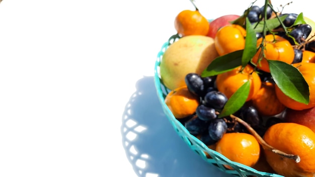 Desenfoque, frutas tropicales en cesta verde sobre fondo blanco.