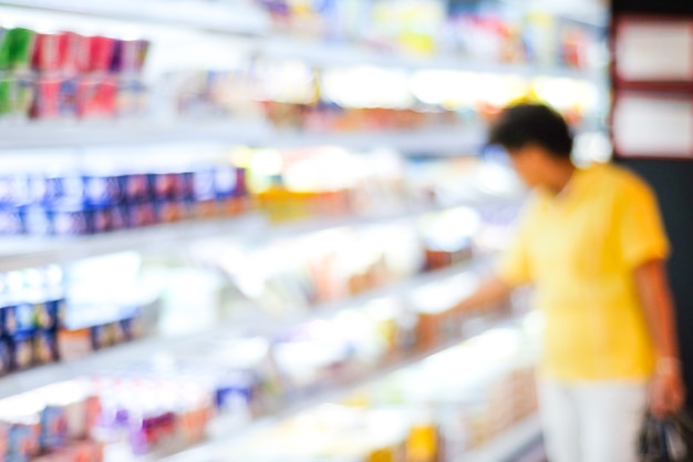 Foto desenfoque a la gente de compras en el estante del producto en el fondo del supermercado