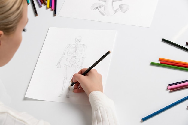 Desenhando a mão de uma jovem desenhando um esqueleto com lápis preto