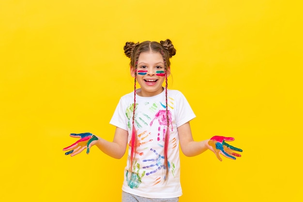 Desenho de arte para crianças uma pequena menina sorridente em um fundo amarelo isolado a criança sujou as mãos com tinta cursos de desenho para crianças