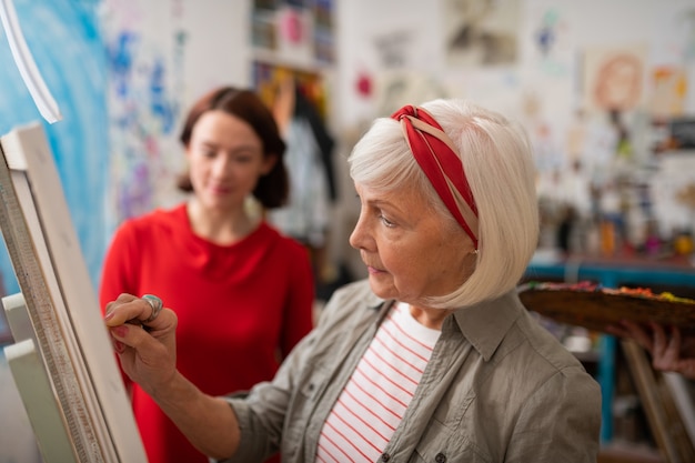 Desenho de artista envelhecido. artista de cabelos grisalhos desenhando em uma tela perto de um estudante curioso