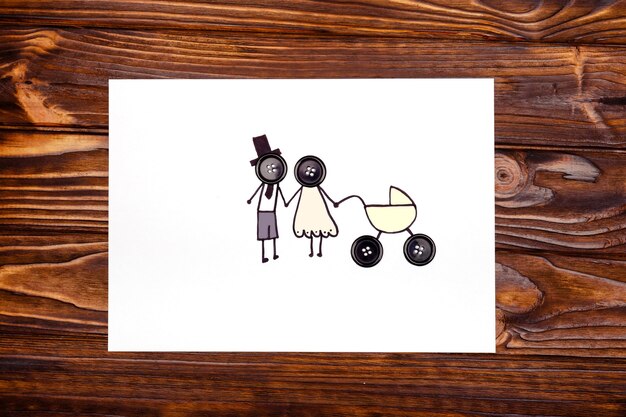 Desenho de jovens pais com um carrinho sobre uma mesa de madeira. o conceito de família. a vista do topo