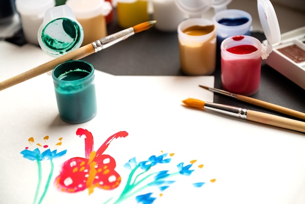 Desenho infantil de borboleta pintado em papel Conjunto de latas de tinta guache e pincel