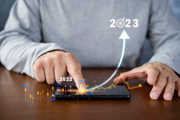 Desenho manual do empresário para aumentar a seta de 2022 a 2023 no smartphone em fundo de sucesso de lucro de tecnologia financeira