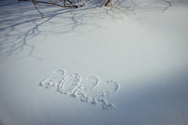 Desenho na neve branca na luz solar. Data de ano novo, figuras 2022, close-up.